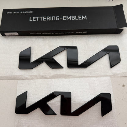 Black KIA lettering emblem with packaging on a light gray background