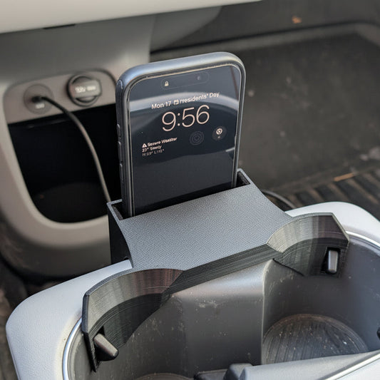 Phone in a car cup holder with digital display showing time and date.